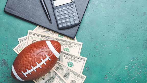football sitting on bills by calculator on table