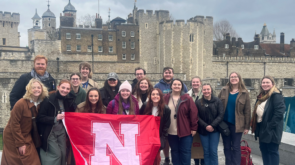 Honors students posing with a Husker flag in London