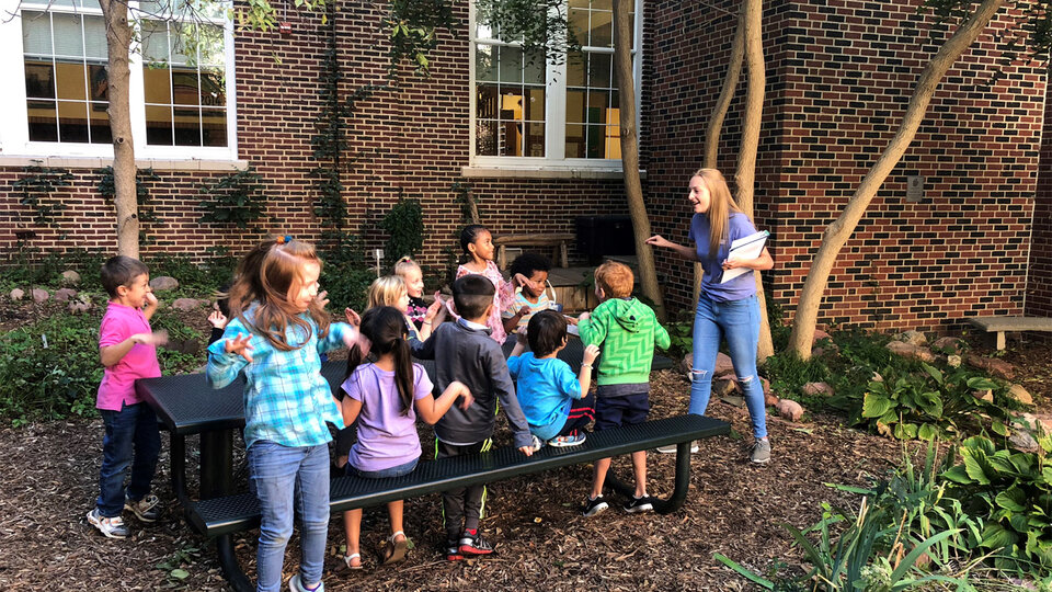 young children sitting on picnic table performing a lead activity