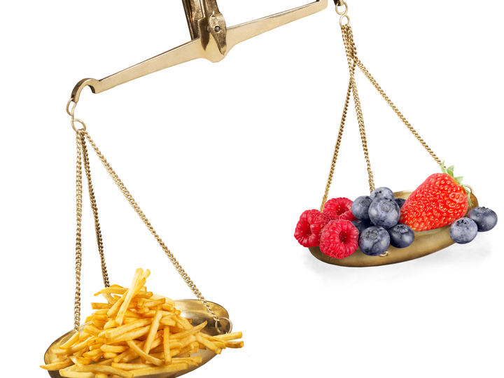 unbalanced scales with french fries weighing more than strawberries, blueberries, and raspberries