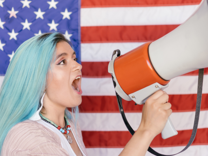 Person with a blowhorn in front of an US flag
