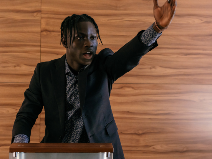 Man standing at a podium with arm outstretched
