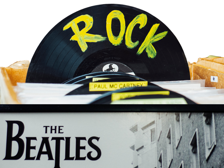 The Beatles brand logo in front of a box of records with one pulled up and the word "rock" on it.