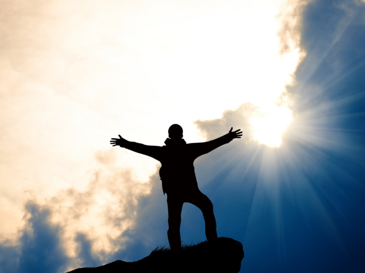 Person with arms stretched out standing on a rock