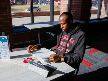 Student studying with a book and computer